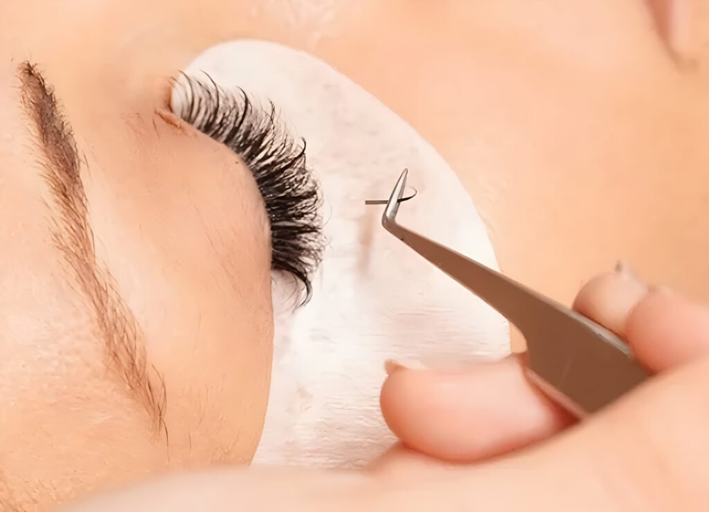 Close-up of a beauty technician applying individual eyelash extensions to a client’s upper lashes