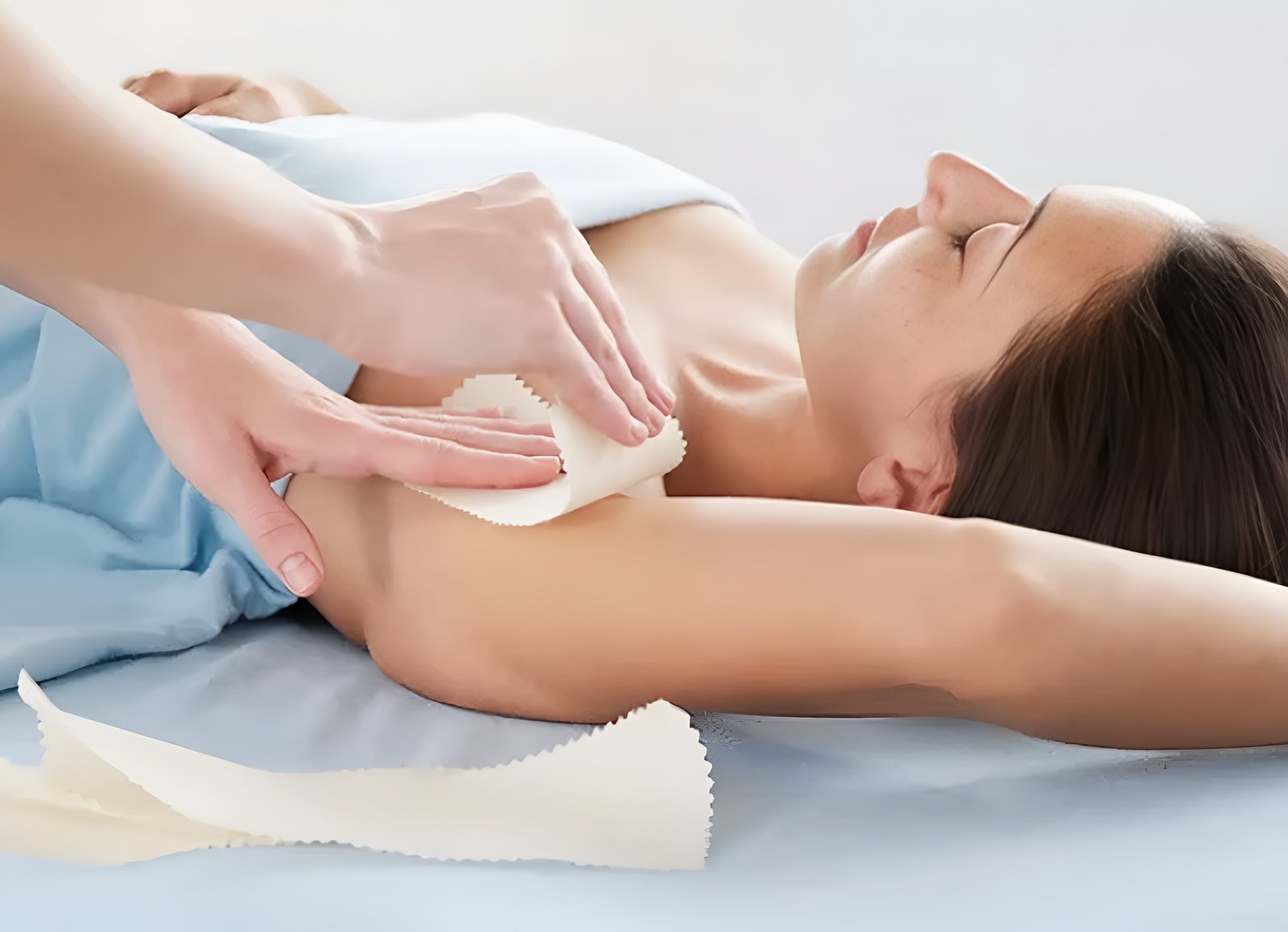 Close-up of an esthetician applying warm wax to a woman’s underarm.