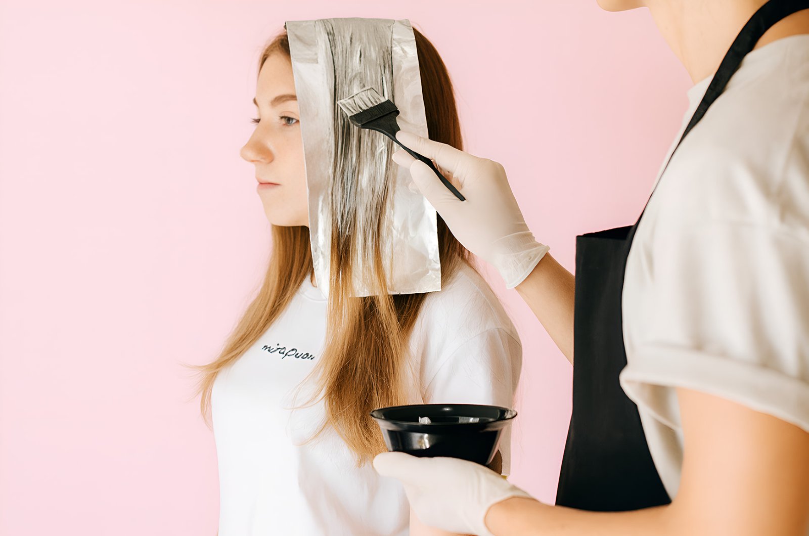 Close-up of stylist applying keratin treatment to client’s hair.