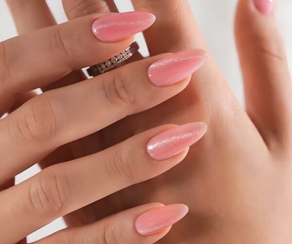 Close-up of a hand with glossy pink soft gel manicure.